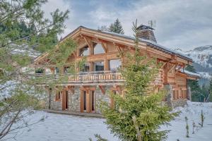 a log home in the snow with snow covered trees at Chalet Indiana in Combloux