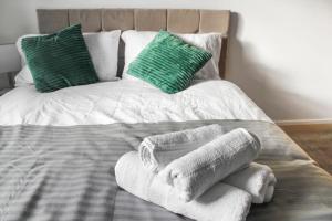 ein Bett mit Handtüchern und grünen Kissen darauf in der Unterkunft Modern 2-Bed in Watford Centre in Watford