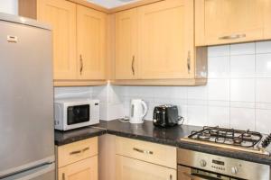a kitchen with wooden cabinets and a white refrigerator at Modern 2-Bed in Watford Centre in Watford