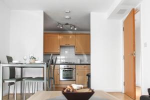 a kitchen with wooden cabinets and a table with a tableablish at Modern 2-Bed in Watford Centre in Watford