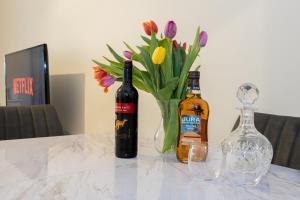 twee flessen wijn en een vaas met bloemen op een tafel bij Church Street Cottage Great Harwood in Great Harwood