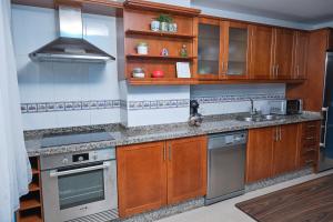 una cocina con armarios de madera y electrodomésticos de acero inoxidable en Piso con garaje El Puente en Santa Cruz de La Palma en Santa Cruz de la Palma