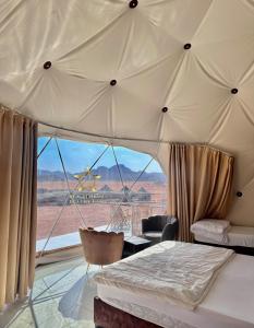 RUM SUNRlSE LUXURY CAMP في وادي رم: غرفة نوم بسرير ومنظر صحراوي
