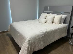 uma cama com lençóis brancos e almofadas num quarto em Ejecutivo penthouse en santo domingo em Santo Domingo