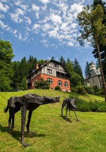 two statues of giraffes in a field with a house at Villa Titina in Miedzygorze