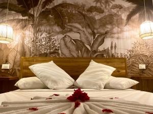 a bed with white pillows and red flowers on it at Lions SUITE&APARTMENT Ocean Front Beach & Pool in Bunju