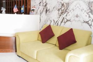 Sofá amarillo con 2 almohadas en una habitación en Hotel Kristal, en Durrës