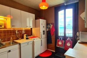uma cozinha com um frigorífico, um lavatório e uma janela em Grand Appartement La Source d'Evian em Évian-les-Bains