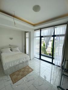 a white bedroom with a bed and large windows at Luxury TownHouse in Douala
