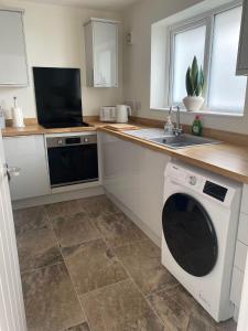 a kitchen with a washing machine and a sink at The Cwtch Pet Friendly Ground Floor Flat Near M4 and Porthcawl in Kenfig Hill