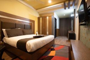 a bedroom with a large bed and a flat screen tv at Hotel Franklein Stay At Delhi Airport in New Delhi