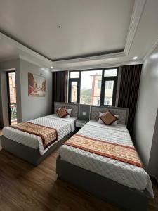 - 2 lits dans une chambre avec fenêtres dans l'établissement Việt Hoàng Hotel Hạ Long, à Hạ Long