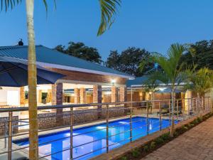 a hotel swimming pool with palm trees in front of a building at The Shrub Lodge in Victoria Falls