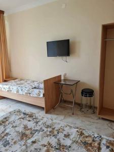 a bedroom with a bed and a table and a tv at Отел Нана in K'obulet'i