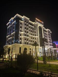 a large white building with lights on it at night at Kangurt Grand Hotel in Dushanbe