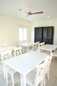 a dining room with white tables and white chairs at Mayilveedu Guest House in Tuticorin
