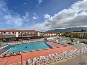 een groot zwembad met stoelen en een gebouw bij 3303 - maison avec piscine in Argelès-sur-Mer
