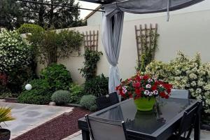 einen Garten mit einem Tisch mit Blumen darauf in der Unterkunft Jolie maison au calme - 300m de la plage - Terrasse - Barbecue in Saint-Michel-Chef-Chef + 20 Fotos