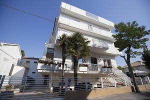 a white building with palm trees in front of it at Hotel Brunella in Rimini