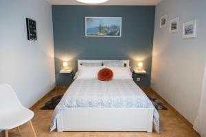 ein Schlafzimmer mit einem weißen Bett und einem roten Kissen darauf in der Unterkunft Jolie maison au calme - 300m de la plage - Terrasse - Barbecue in Saint-Michel-Chef-Chef