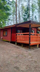 a small red cabin with a porch in the woods at Oleandria-,, Domek Mięta" in Biskupiec