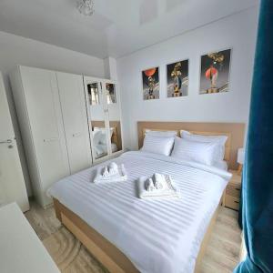1 dormitorio con 1 cama blanca y 2 toallas en Cozy SoRaDa 2 apartment, en Bragadiru
