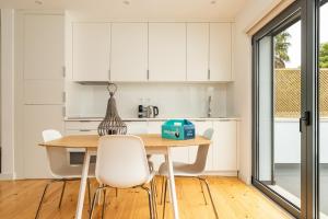 a kitchen with white cabinets and a wooden table and chairs at Belém Design Apartments by Homing in Lisbon