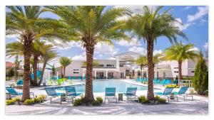 a resort pool with palm trees and blue chairs at StarWar Retreat 3D 12BR 11.5BA Villa Pool BBQ in Kissimmee