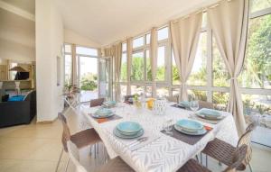 uma sala de jantar com uma mesa branca com cadeiras e janelas em Il giardino di Afrodite em Marinella di Selinunte