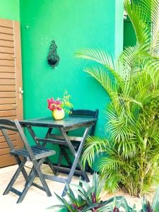 a table and chairs in front of a green wall at Suítes Green Village Flecheiras in Flecheiras