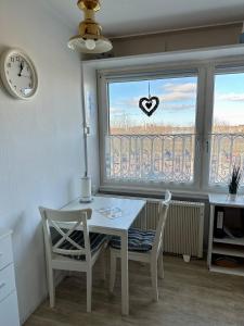 una cocina con mesa y sillas y una ventana con un signo cardiaco en Fehmarn Ferienwohnung Weber Captains Corner Südstrand WHG 59-110 en Fehmarn