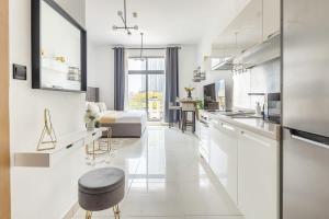 a kitchen and living room with white cabinets and a couch at Frank Porter - Claren Tower in Dubai