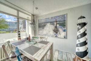 ein Esszimmer mit einem Tisch und einem Bild eines Leuchtturms in der Unterkunft Ferienpark - Haus C, App 0CEG06 in Heiligenhafen