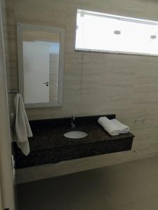 La salle de bains est pourvue d'un lavabo et d'un miroir. dans l'établissement Pousada Floresta, à Joinville