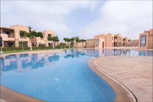 uma grande piscina em frente a alguns edifícios em Maison 3 chambres em Marrakech
