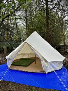er staat een tent op een blauw zeil bij WoodLands Basic Bell Tent 3 in Grantham