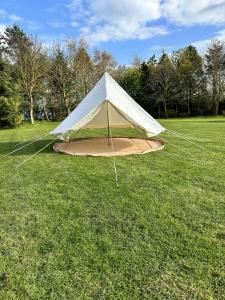 une tente blanche au milieu d'un champ dans l'établissement WoodLands Basic Bell Tent 2, à Grantham