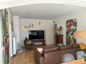 ein Wohnzimmer mit einem Sofa und einem Flachbild-TV in der Unterkunft Logement cosy avec piscine ,parking et jardin in Villeneuve-lès-Avignon