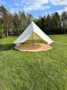 ein Zelt in der Mitte eines Feldes in der Unterkunft WoodLands Basic Bell Tent in Grantham