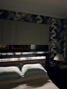 a bed in a bedroom with a headboard and a lamp at Acogedor chalet a 5 minutos de las playas. in Mar del Plata