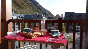 a table with a red table cloth and food on a balcony at Reflets montagnards in Vignec