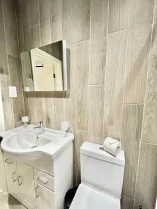 a bathroom with a sink and a toilet and a mirror at High-Spec Apartment in London - City Centre & Next To Tube in Ealing