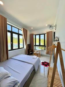 a bedroom with a bed and a table and windows at Hotel Vũng Găng in Vĩnh Hy