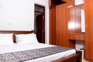 a bedroom with a bed and wooden cabinets at TANISHIA APARTMENTS in Mombasa