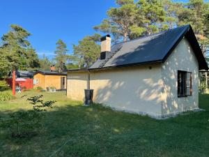 ein kleines weißes Haus mit schwarzem Dach in der Unterkunft Mysig stuga i Rute med stor trädgård in Lärbro