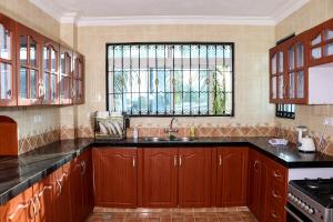 Una cocina con armarios de madera y un fregadero y una ventana. en TANISHIA APARTMENTS, en Mombasa 10 fotos más