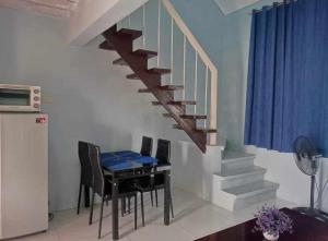 uma sala de jantar com uma mesa e uma escada em Merj's Guest House in Cavite em Trece Martires