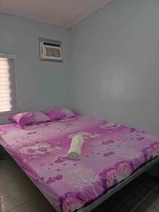 uma cama com uma colcha roxa e uma almofada em Merj's Guest House in Cavite em Trece Martires