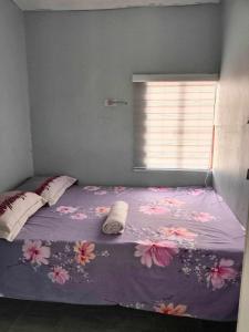 uma cama com um cobertor roxo com flores em Merj's Guest House in Cavite em Trece Martires