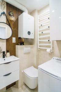 a white bathroom with a toilet and a sink at Apartament Kulturalny in Sanok
